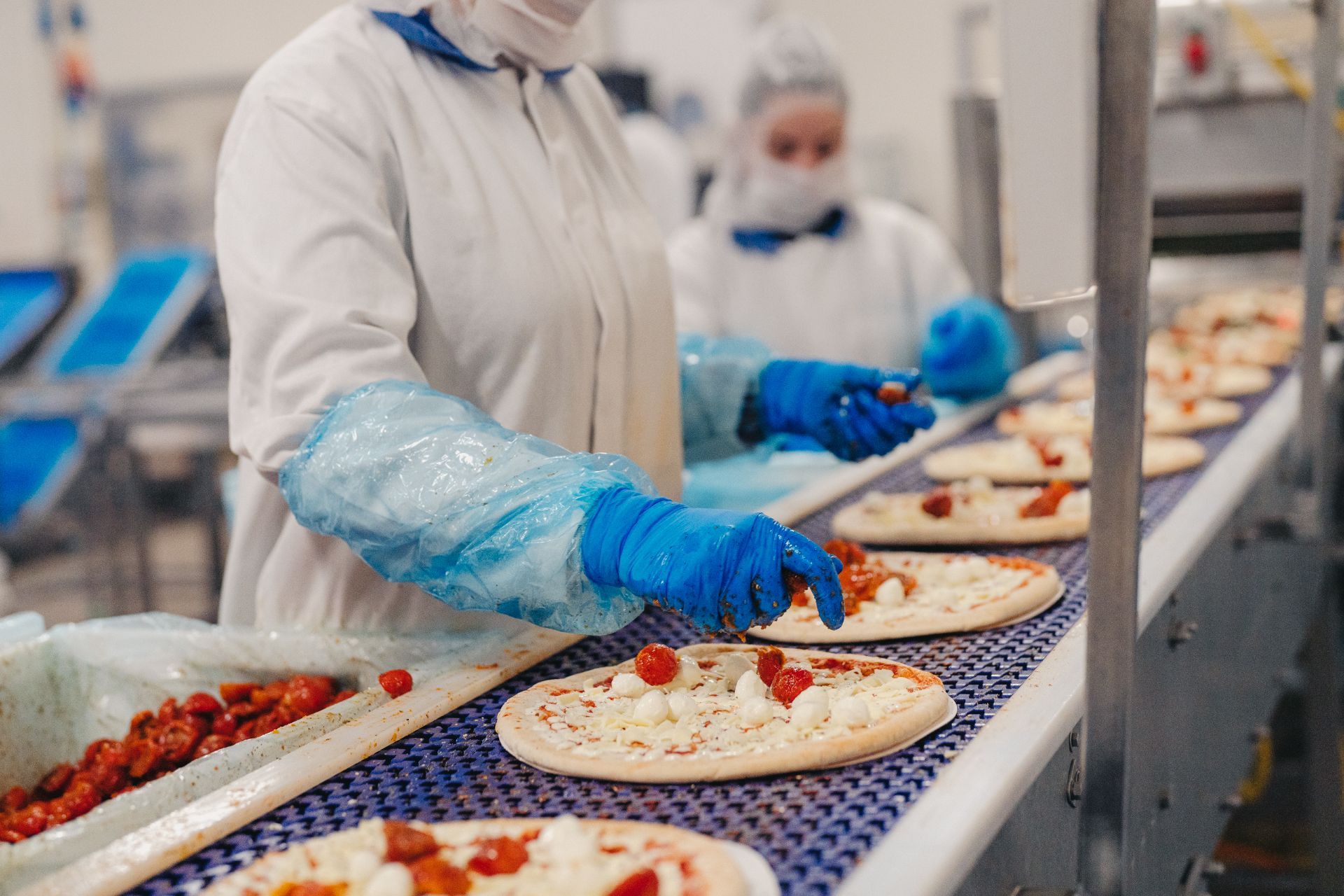 Werknemers leggen topping op pizza