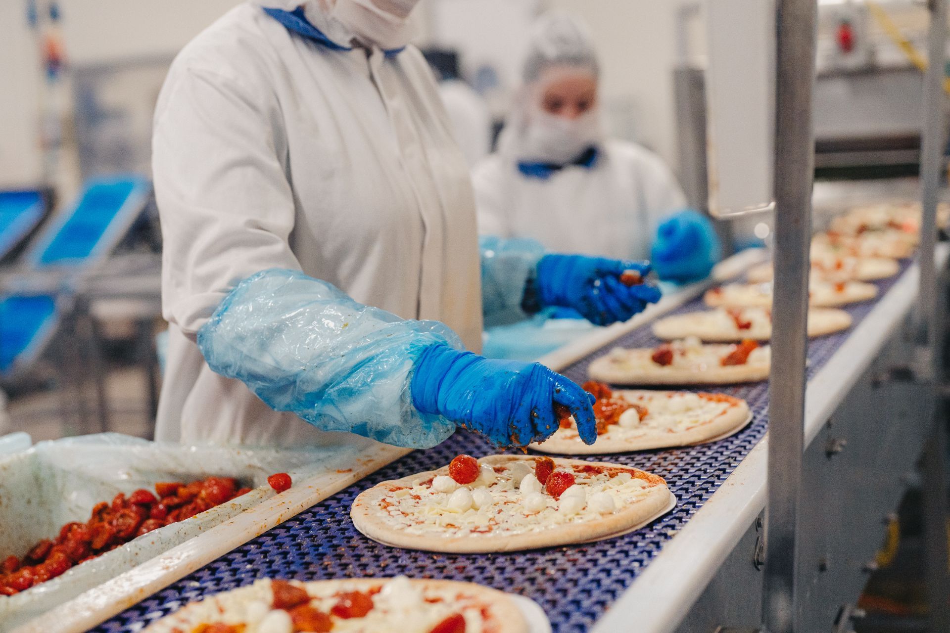 Employees put toppings on the pizza